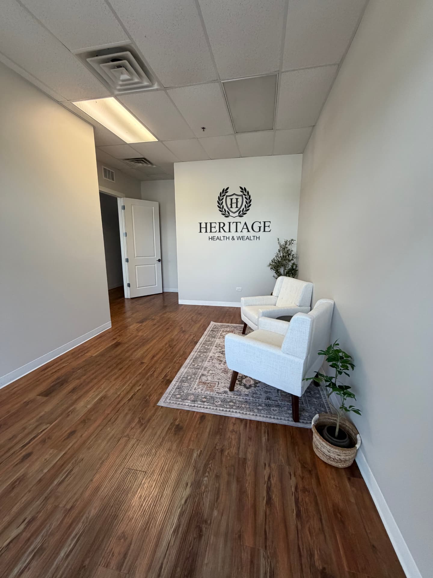 Front lobby with two armchairs, a rug and a tenant logo on the wall.