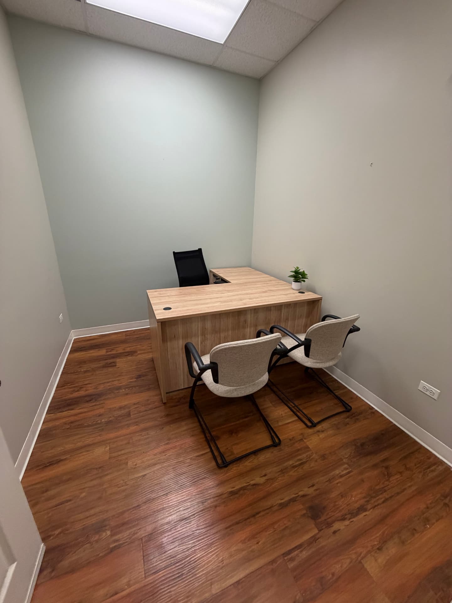 Standard private suite with an L-shaped desk and two guest chairs.